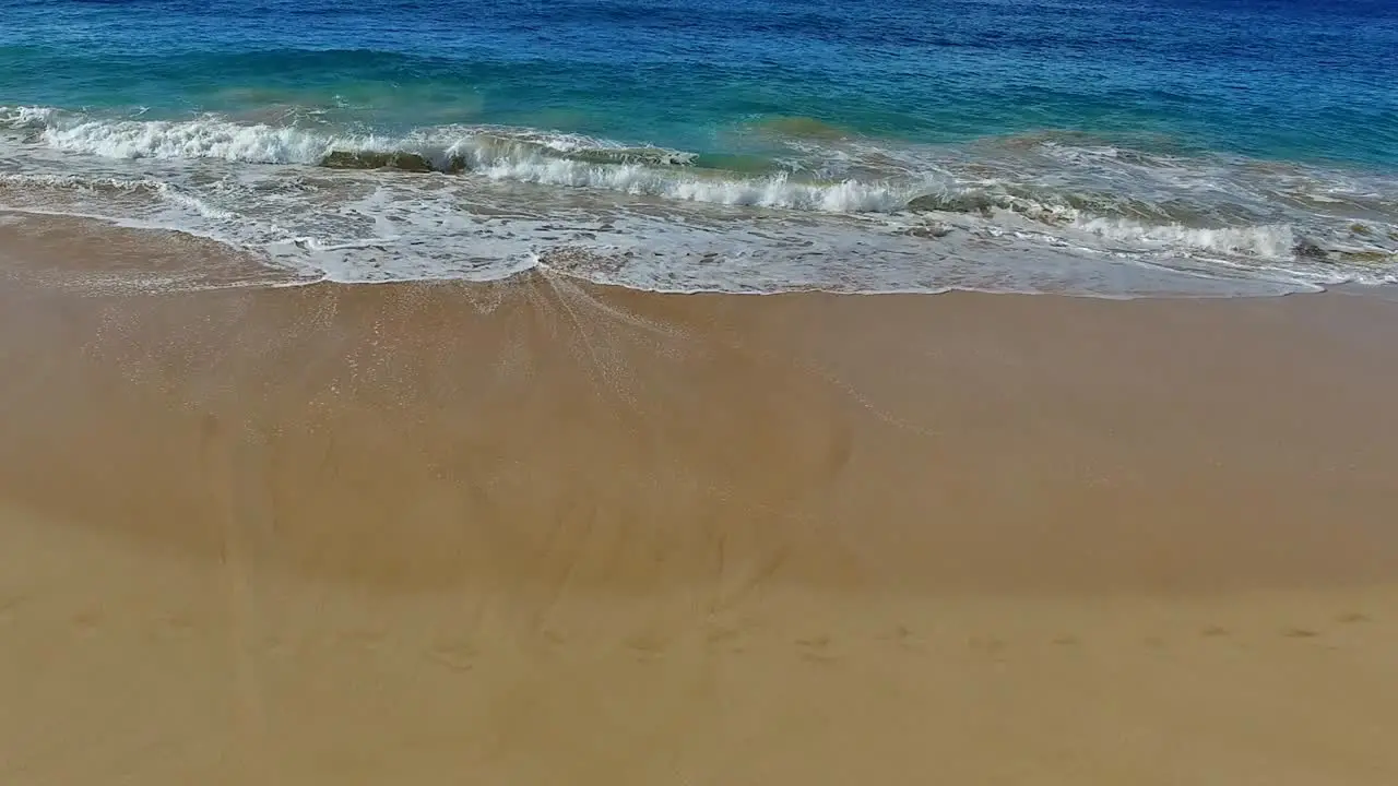 Panning waves crashing on sandy beach in Maui Hawaii with beautiful sky and water no land in the background