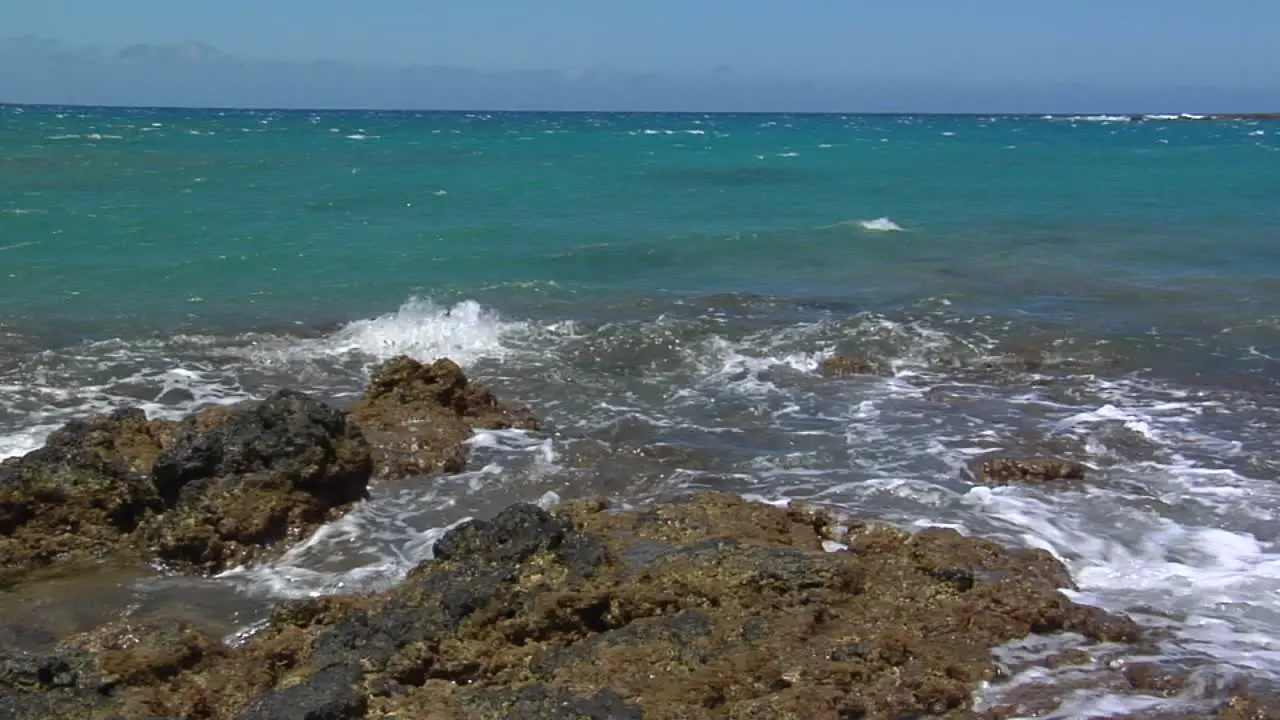 Pan Across Ocean Waves Lapping Against Volcanic Shore