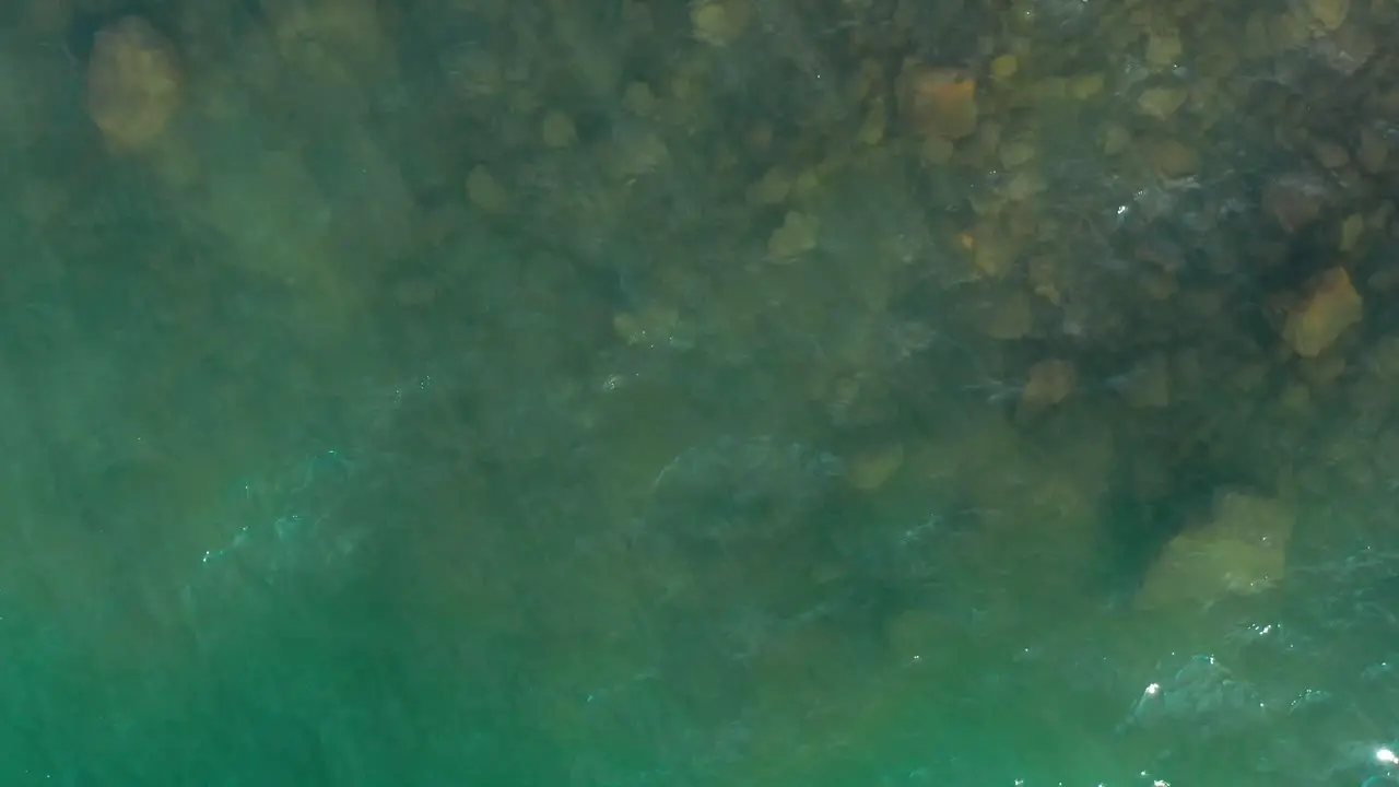 Shimmering beach water appears green from above