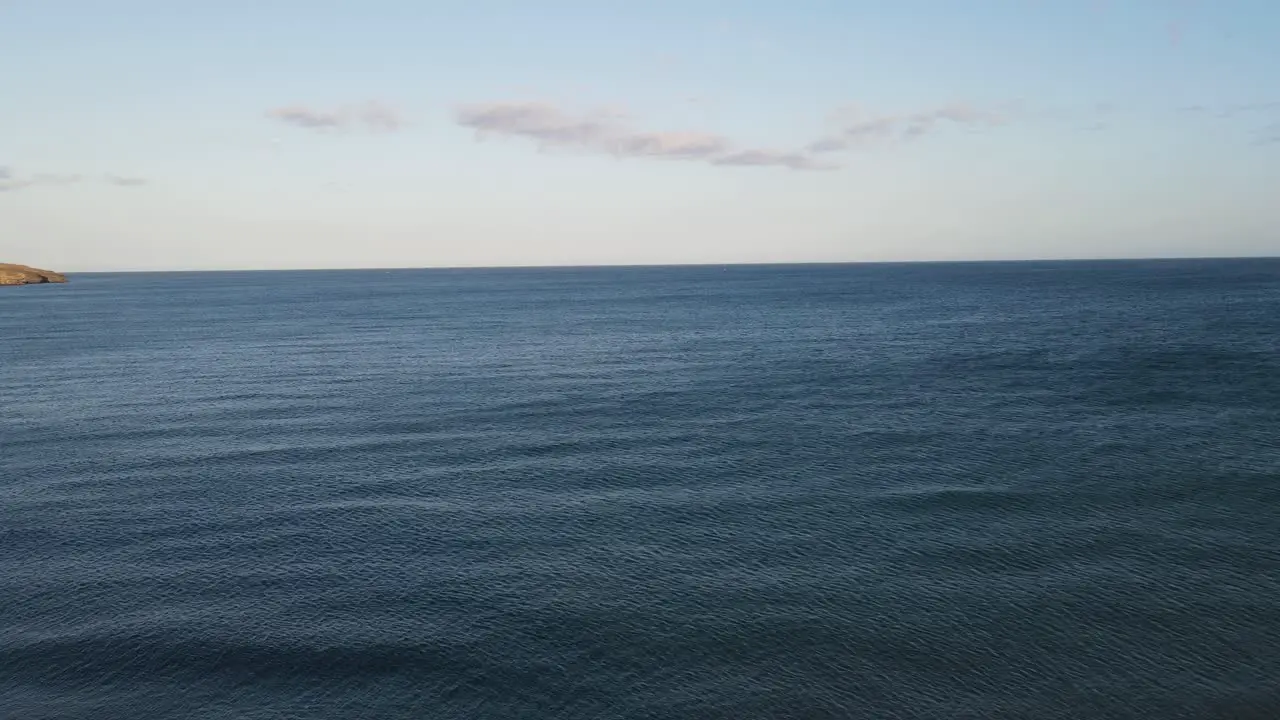 Aerial drone shot of a woman standing on a cliff in front of the ocean Canary Islands Fuerteventura