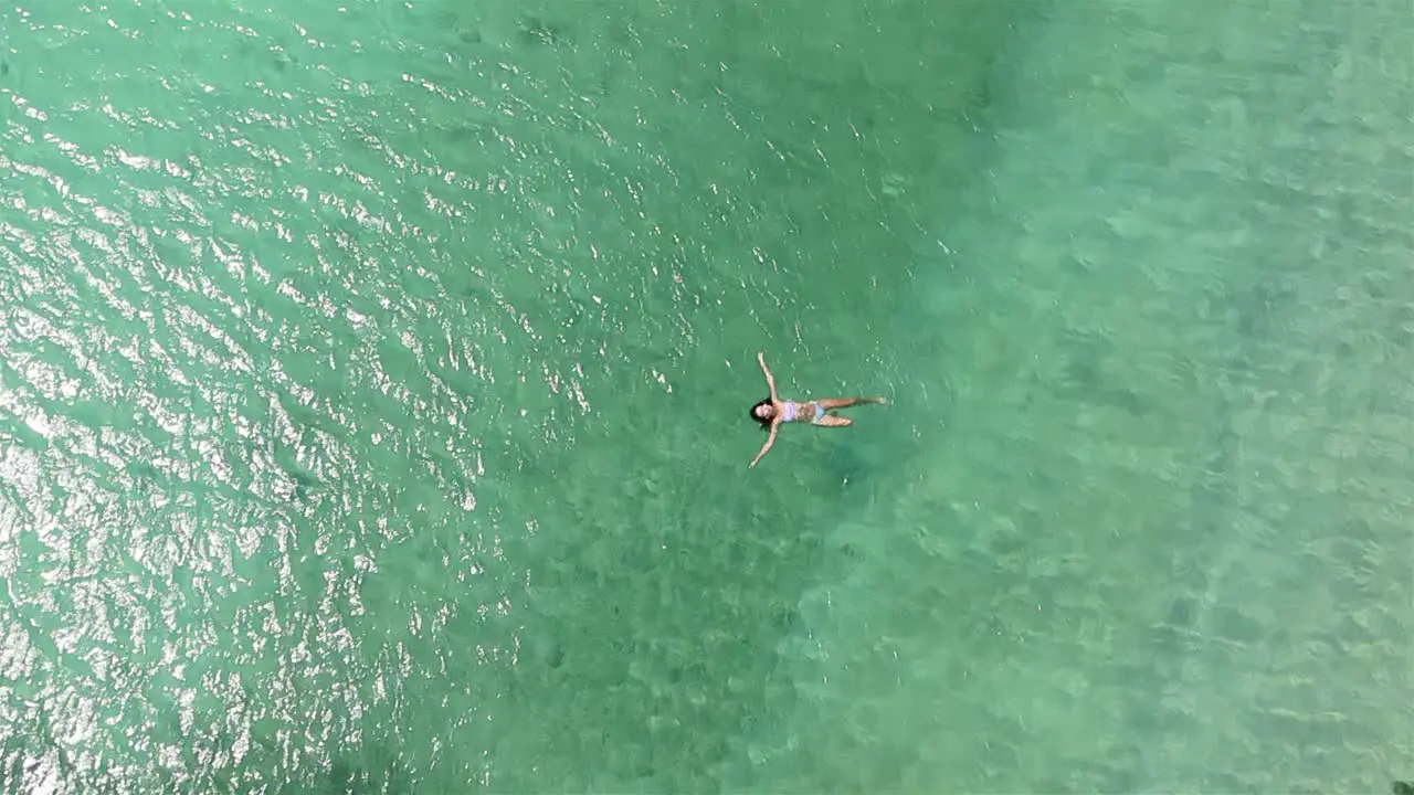 4k aerial drone footage of a lone women in a bikini swimming in the beautiful clear coastal waves of a resort in Ko Larn Island Thailand