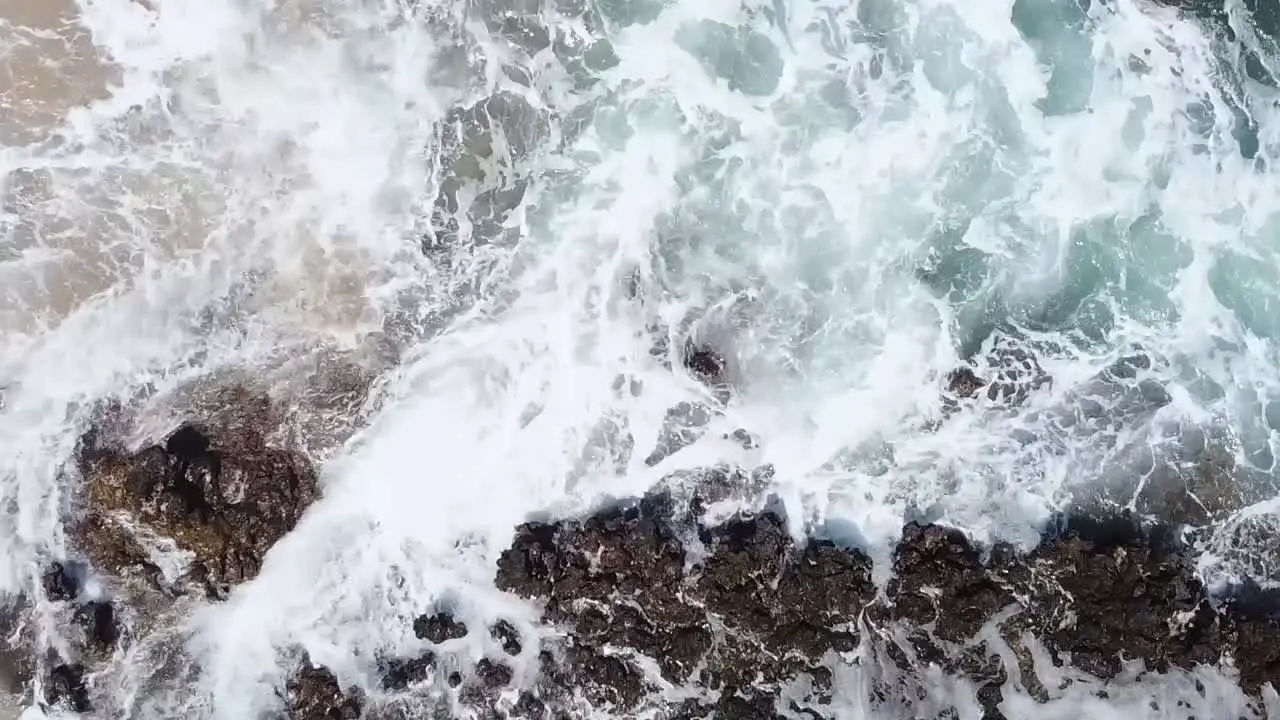 Drone aerial over ocean waves rock crashing beach