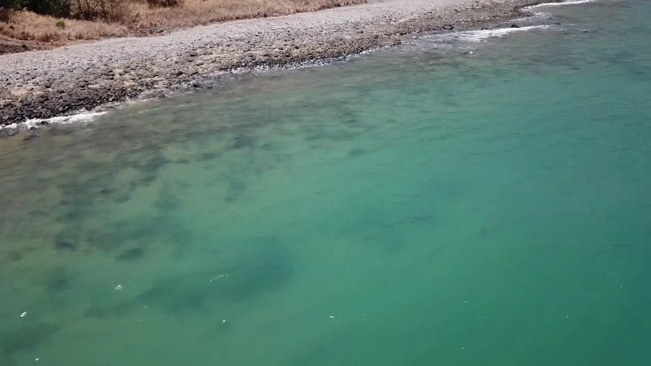 Drone going backwards to reveal tropical mountain and beach