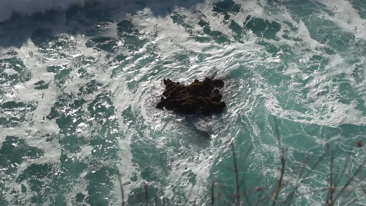 White ware wave rolling over uncovered part of a dark colored reef in Bali Indonesia