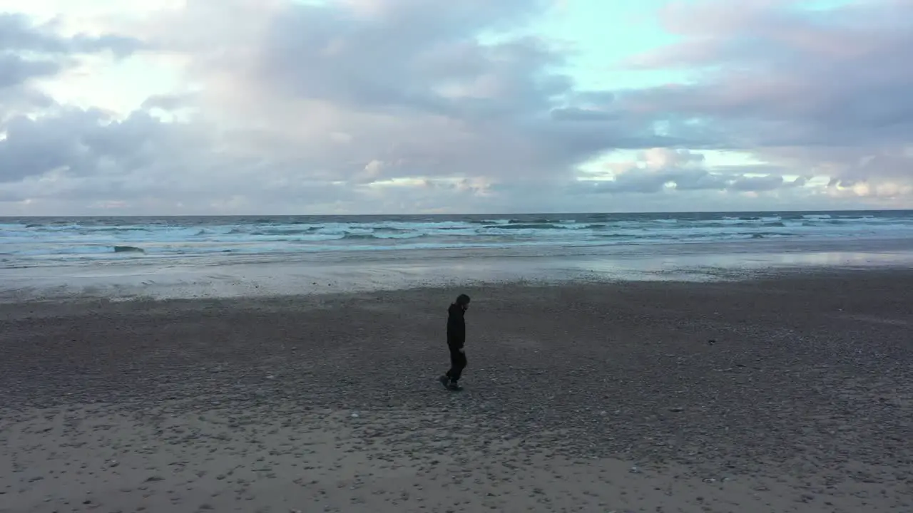 Man walks alone along empty deserted beach during pandemic Covid-19