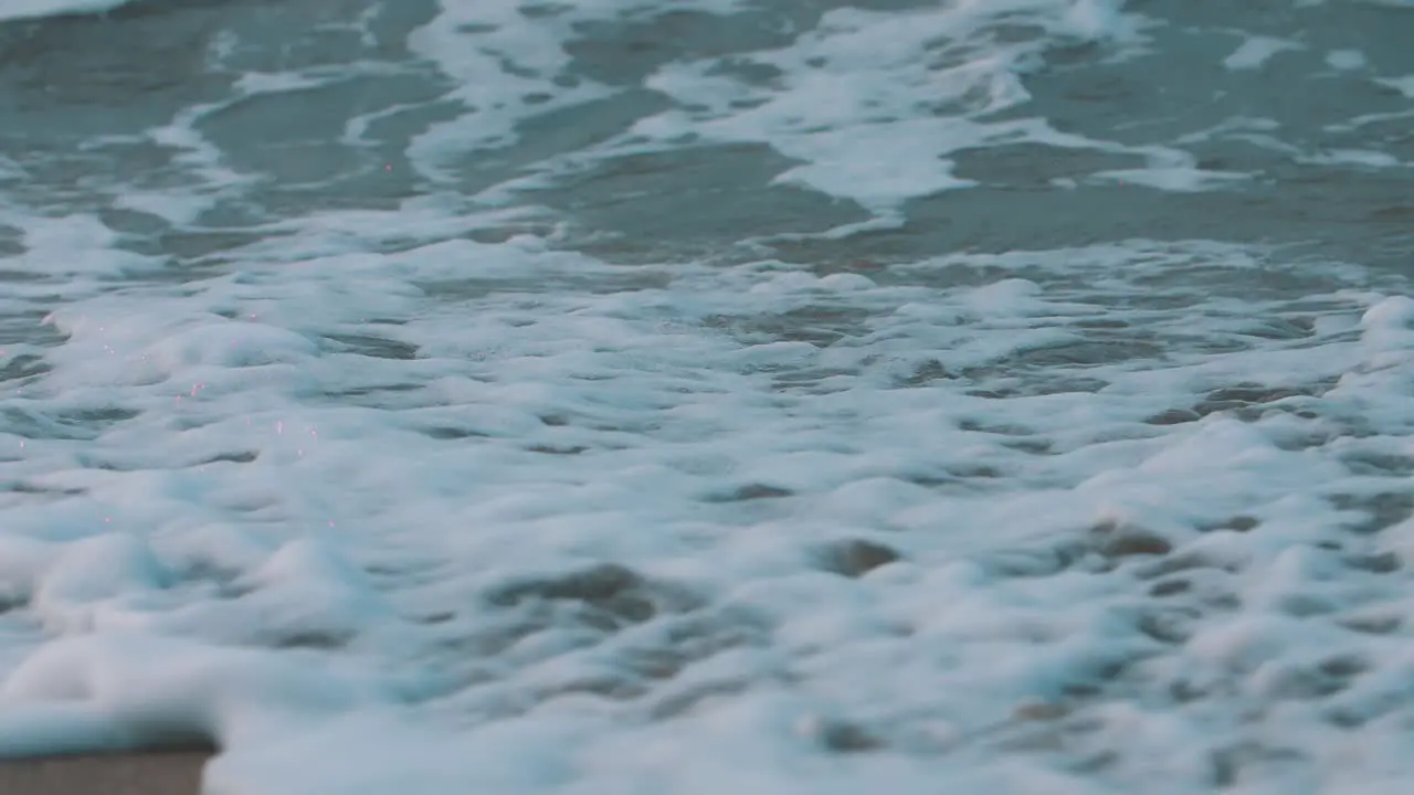 close-up foam of the waves crashing on the sand in slow-motion