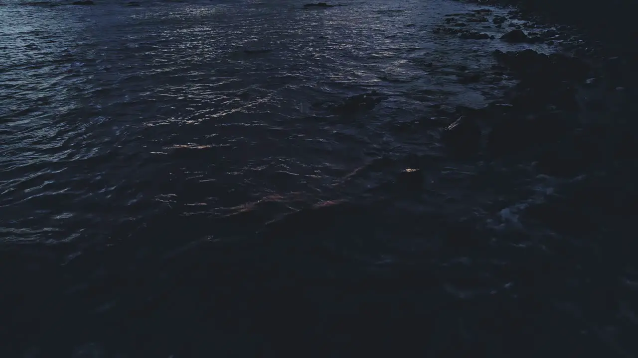 Aerial view of ocean waves tilting up and moving forward during dusk or dawn