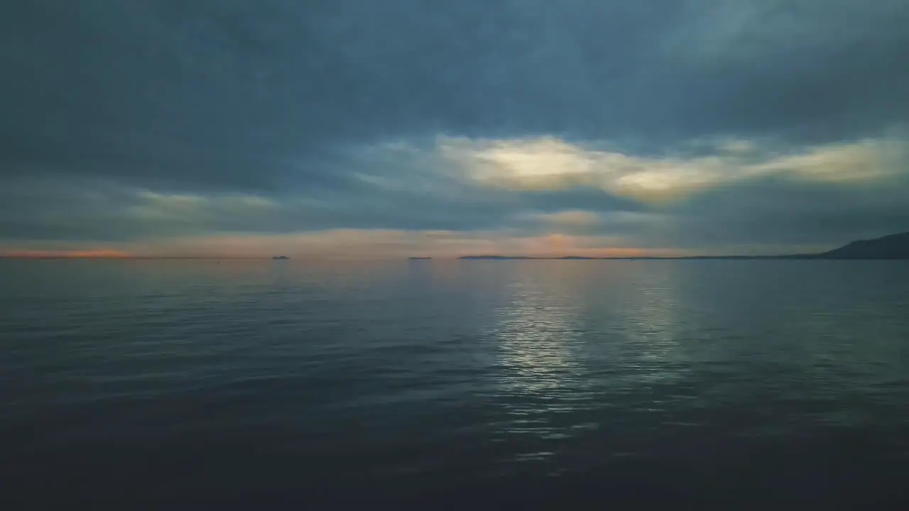 Aerial view at the evening over a calm sea slowly moving backwards