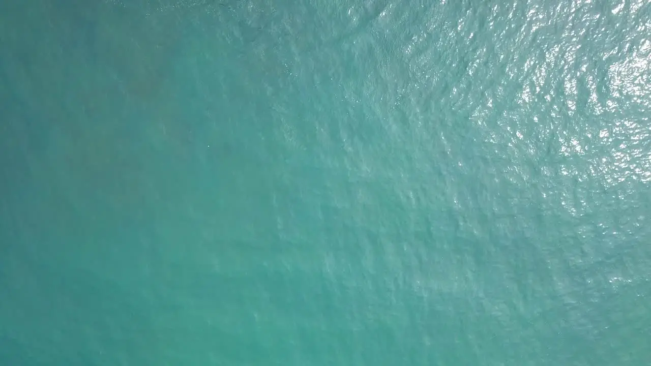 Overhead drone shot of Calm bluish sea surface with reflection of sunlight