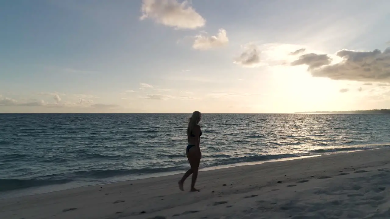 Silhouette of woman running and walking on exotic White Island beach at sunrise