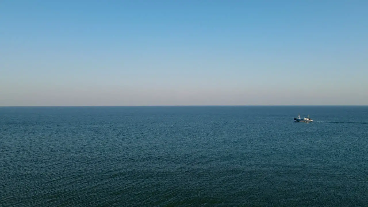 A fishing boat sails on the calm Baltic Sea the rolling sea and clear sky on the horizon Hel Poland