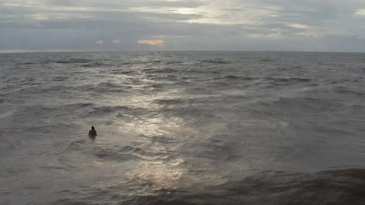 Man sitting up on the surf board in rough sea in the evening Surfer sitting on the surfboard during sunset in Bali