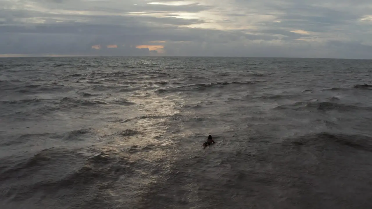 Man floating on the surf board in sea waves on a cloudy day Surfer lying on the surfboard at evening in the ocean