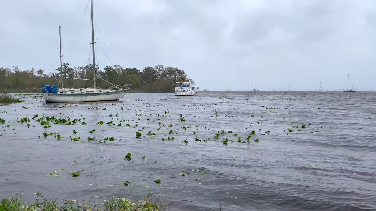 Sailboats anchored in rough waters before hurricane storm with masts down