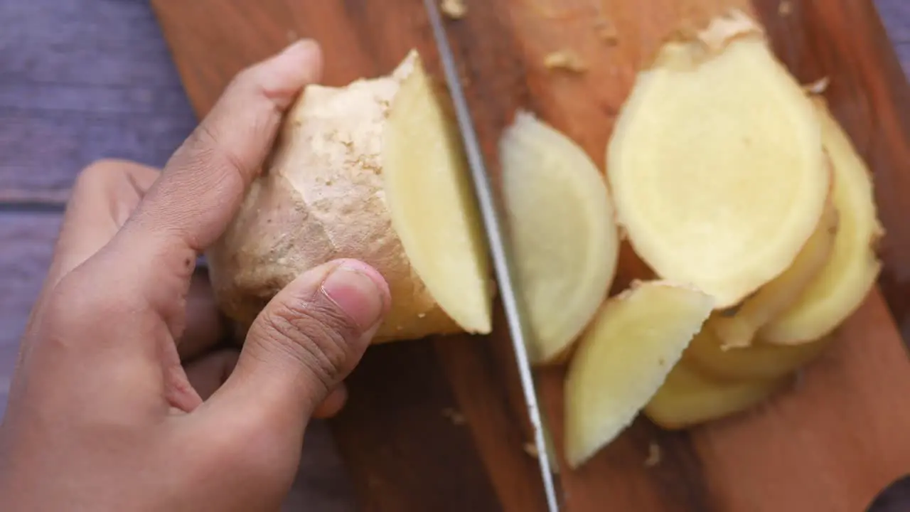 Cutting gingers with knife on chopping board