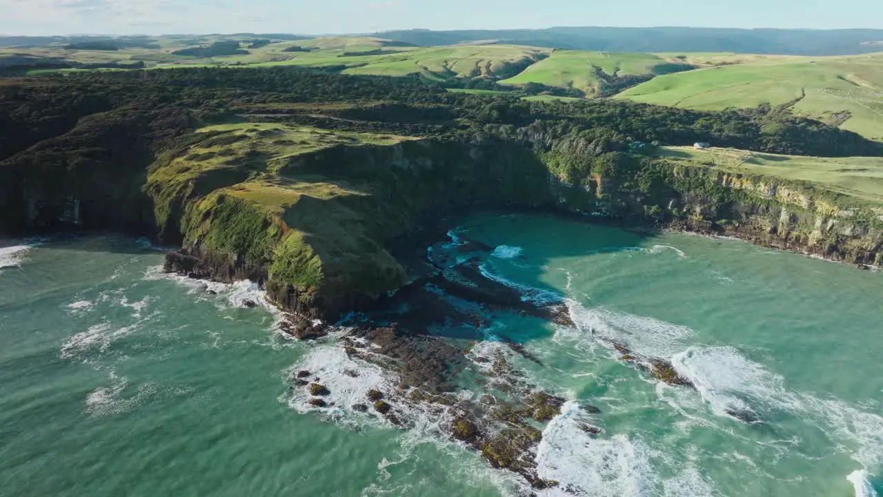 Aerial view of wild and rugged steep cliff coastline with rough sea and crashing waves in New Zealand Aotearoa