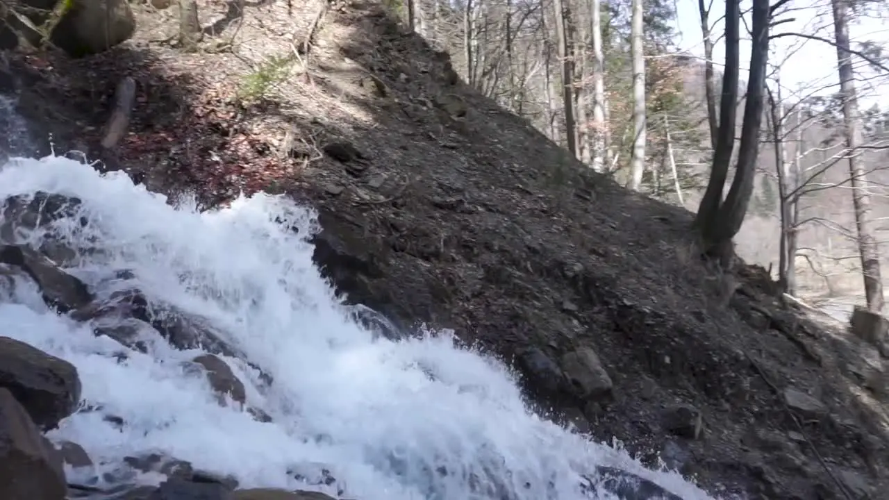 Pan shot of roaring waterfall on the hill