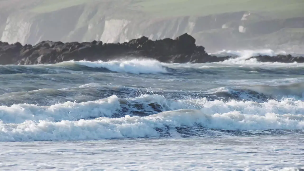 Two kitesurfers whizzing by in rolling waves of the coast of Ireland