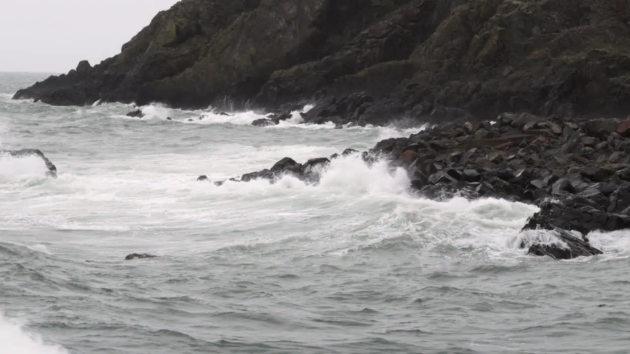 Rough Autumn tide crashes in on dark rocks in the small village of Port Patrick Dumfries and Galloway Scotland