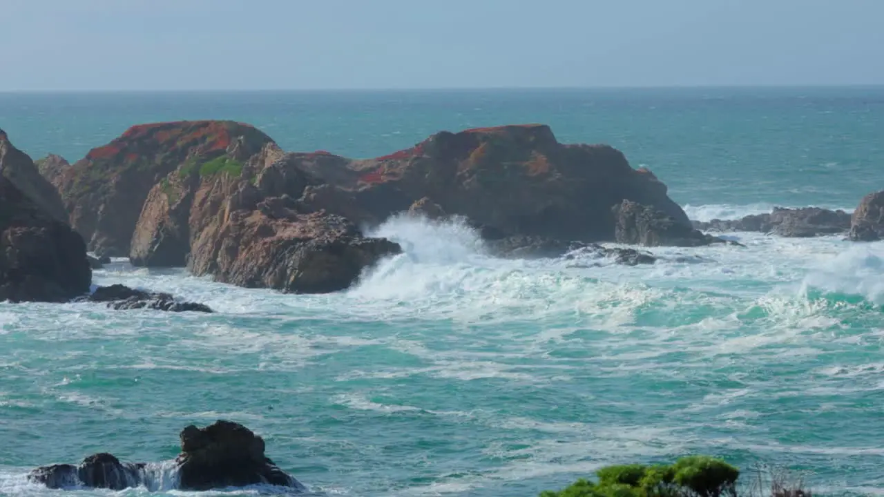 Large waves crashing against rocky island on Big Sur Coastline in Garrapata cliffs covered in red iceplant in Slow Motion