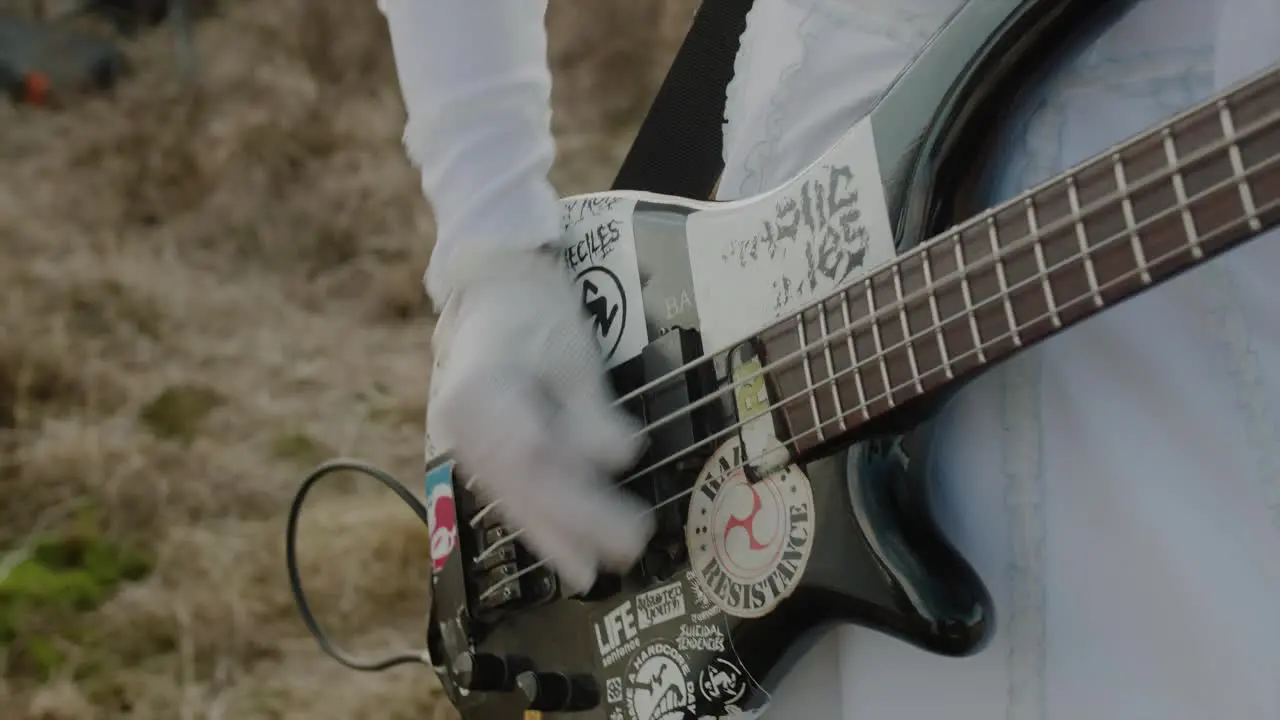 close up bride playing bass in wedding dress in desert