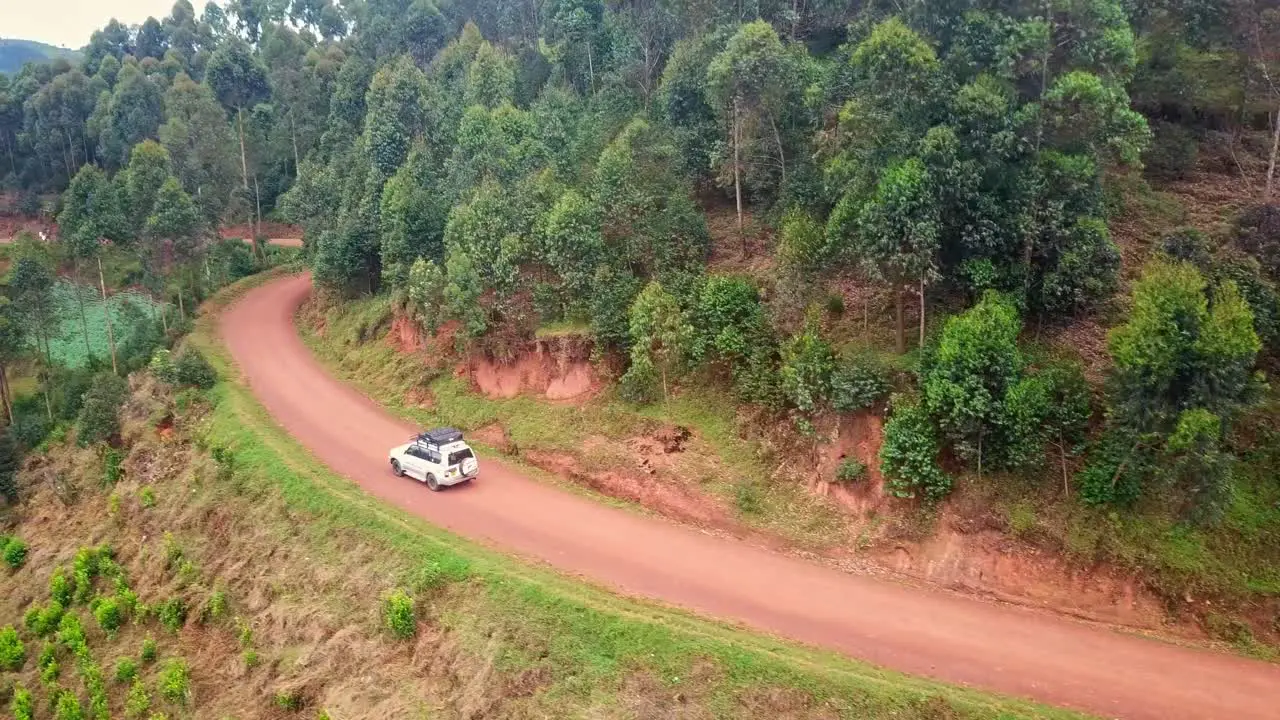 Off-road SUV Driving On Dirt Road By The Mountain With Forest In Uganda Africa