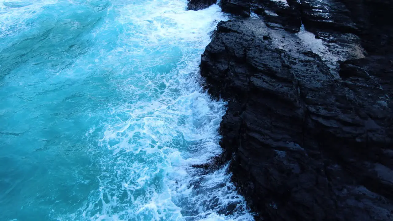 drone close up of white wash and waves breaking on hawaiian cliff and rocks