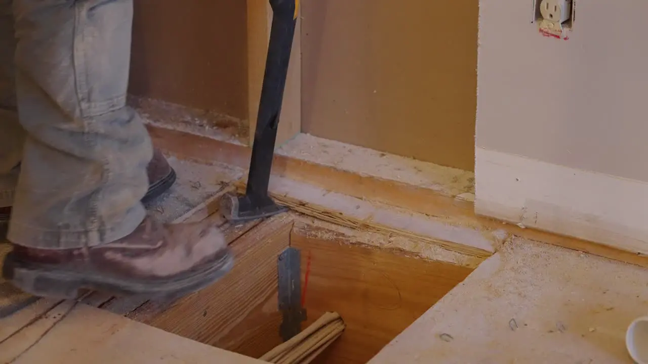 Construction worker kicking and prying wood