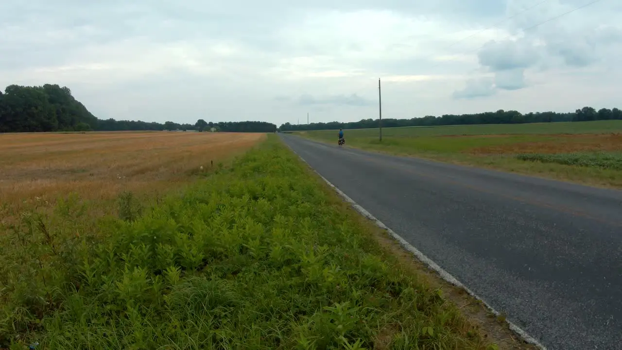 Cyclist bikepacking on country road with flashing head safety light rear view