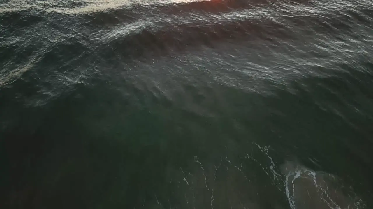 Drone aerial over waves during sunrise at beach