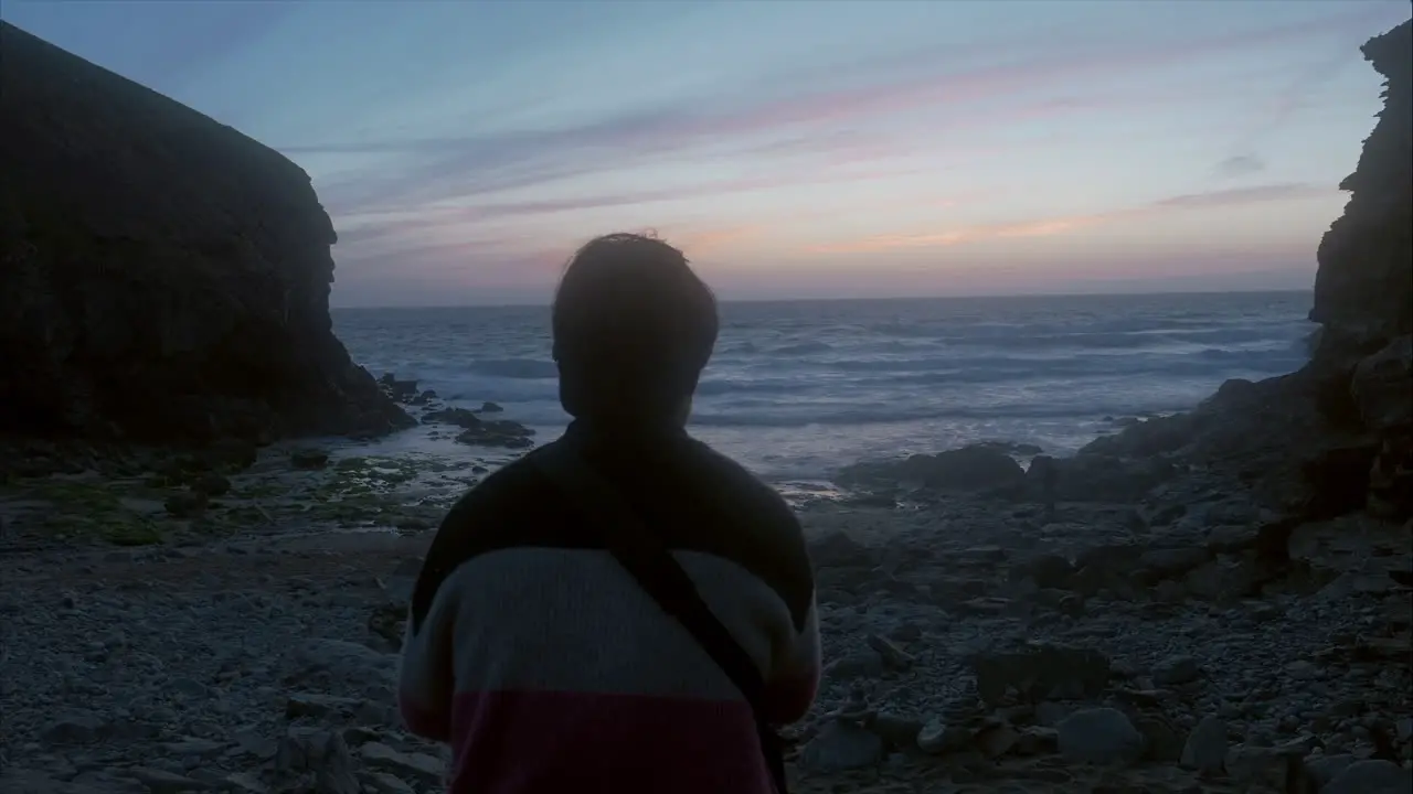 Man reflecting on life looking out at sea and sky with blue red and golden colours wide shot