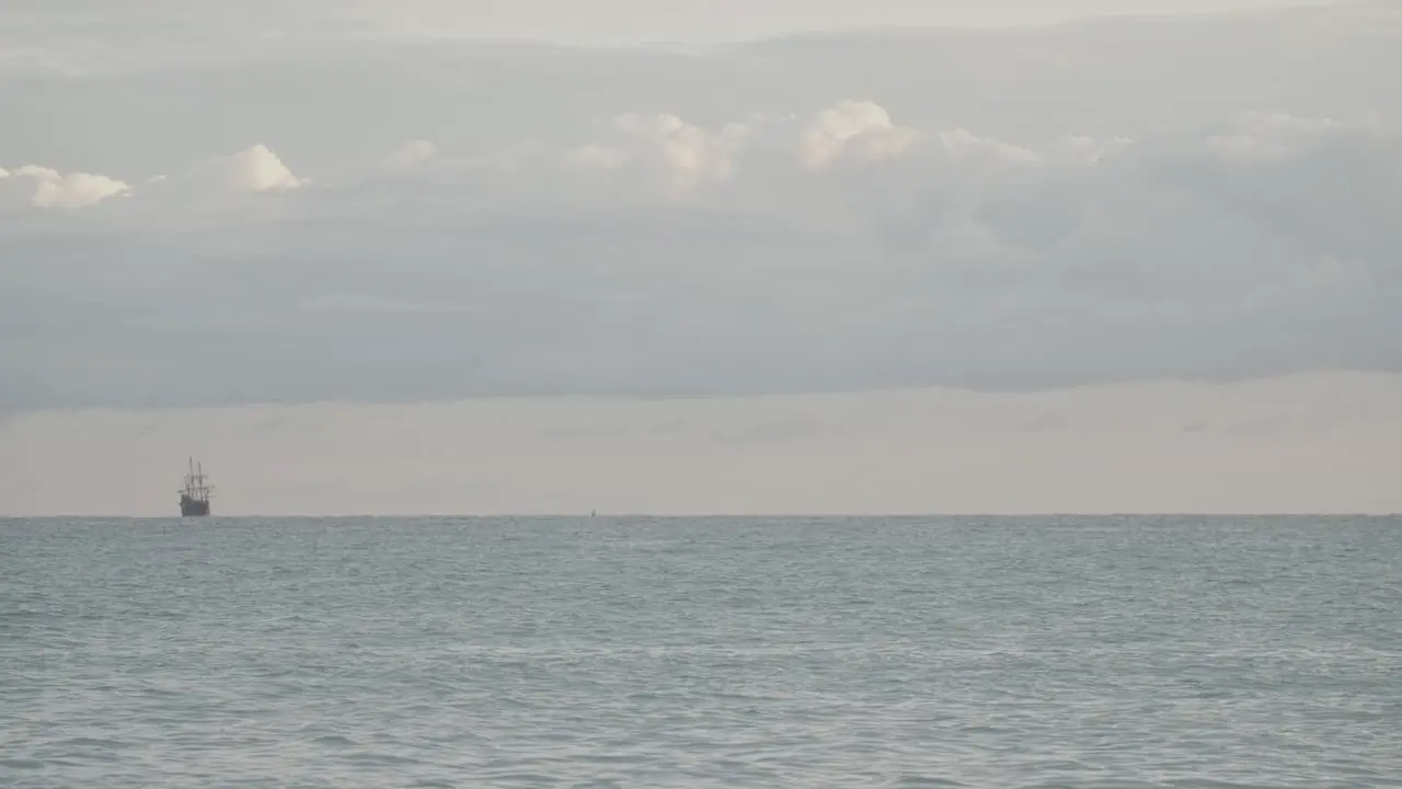 16th Century Galleon Andalucia replica ship sailing in the distance in the calm Mediterranean sea in a cloudy day at sunrise