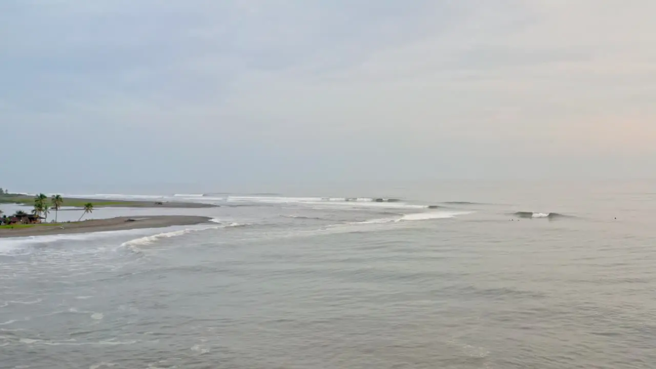 Aerial waves rolling in to tropical sandy beach overcast sunset