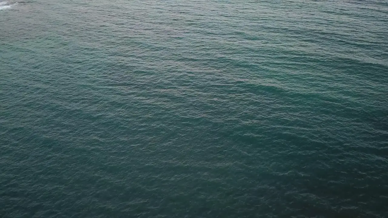 Extended drone shot of ocean water at sunset