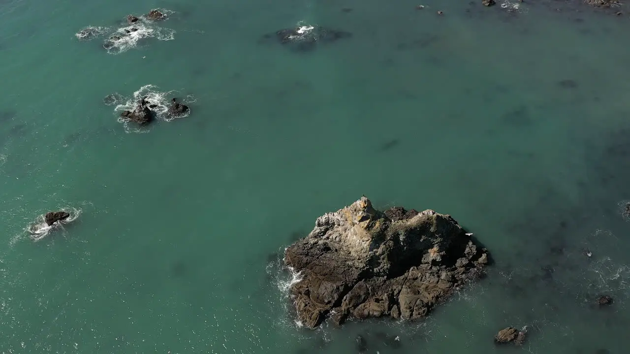 Birds fly over sea stack in turquoise water