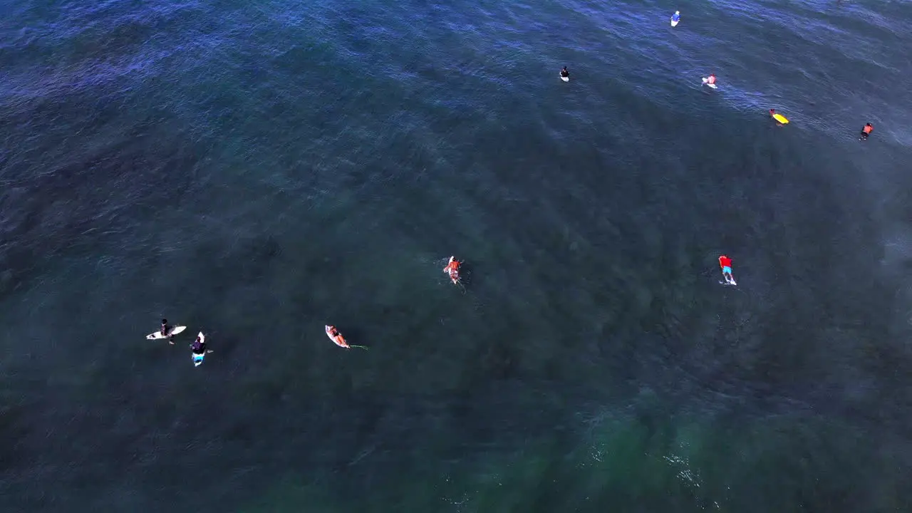 Surfers floating in the ocean while waves crash around them in Rincon Puerto Rico during a clear day with blue sky