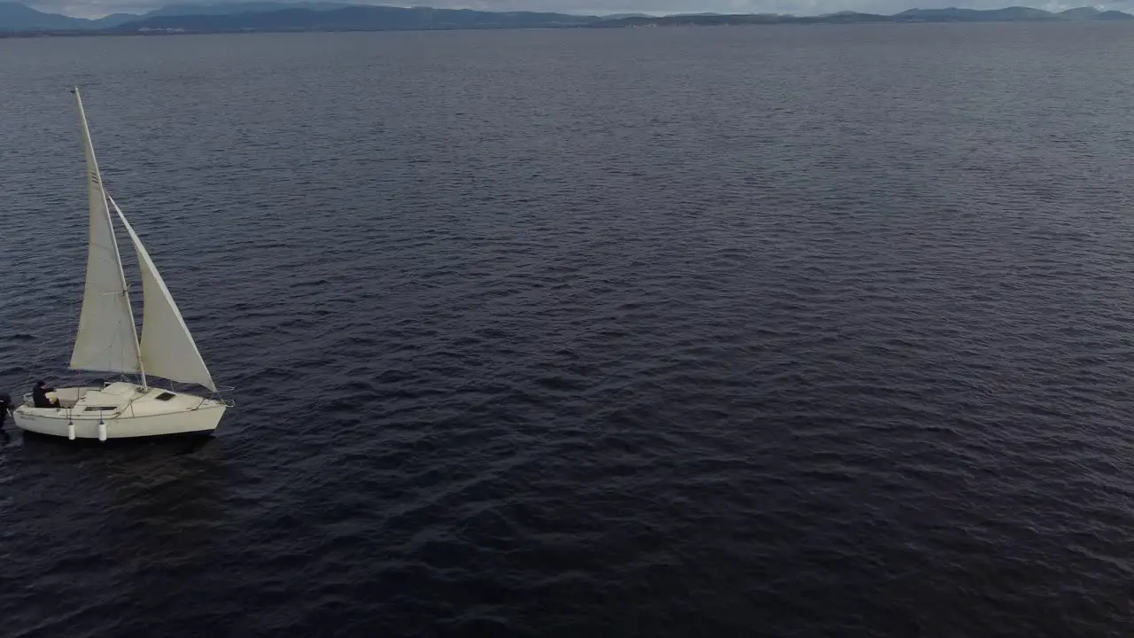 Aerial drone of a small sailboat sailing in calm water Sardinia day