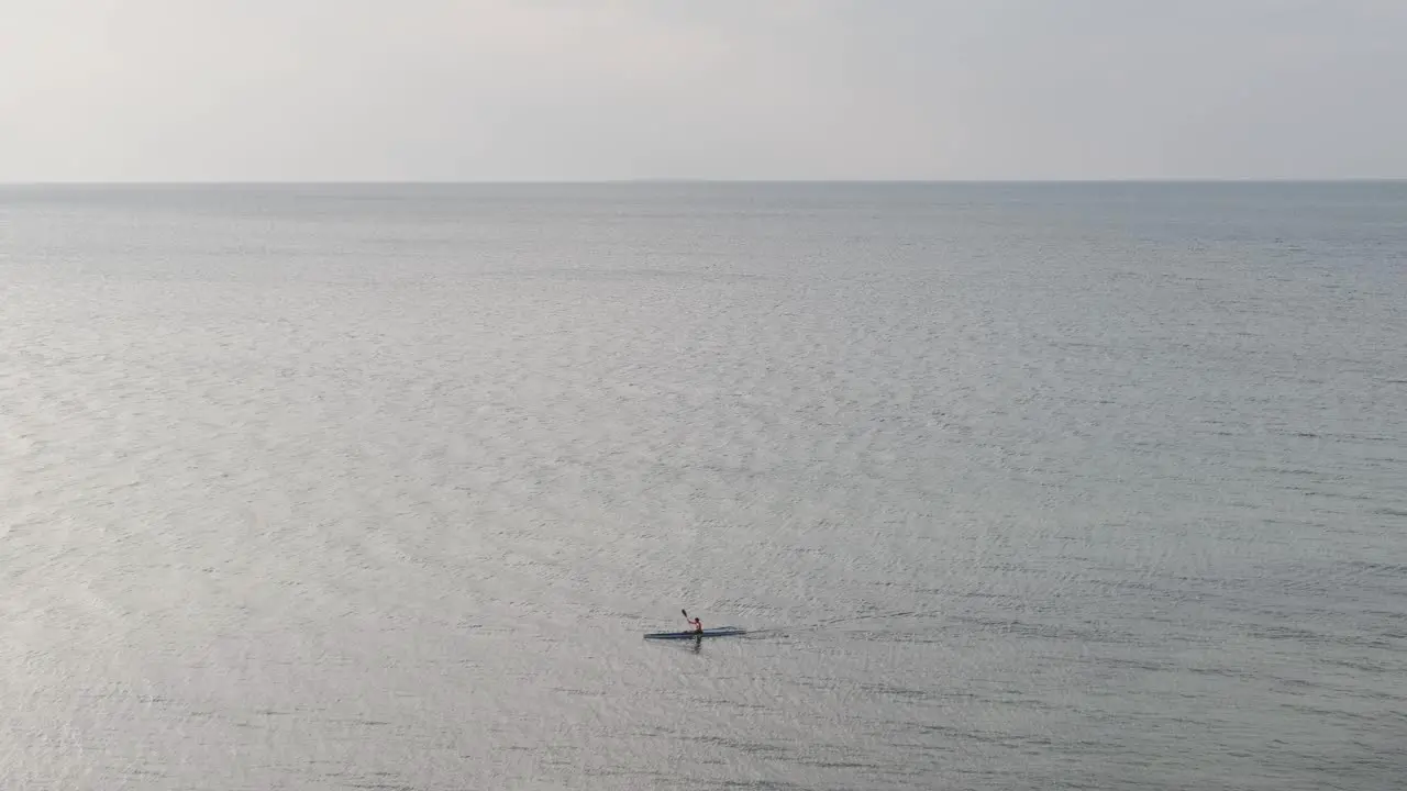 Wide view of sea with single person canoeing along the sea