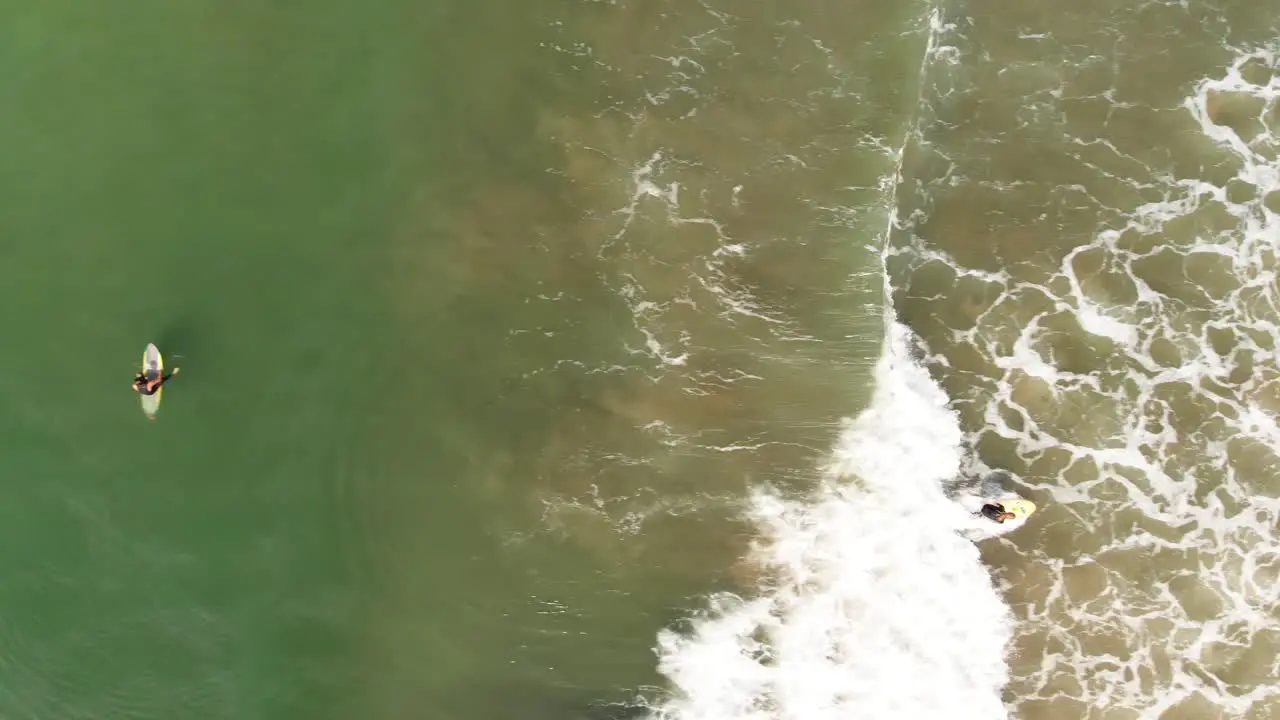 Aerial shot of two female surfers one catching a wave in southern California