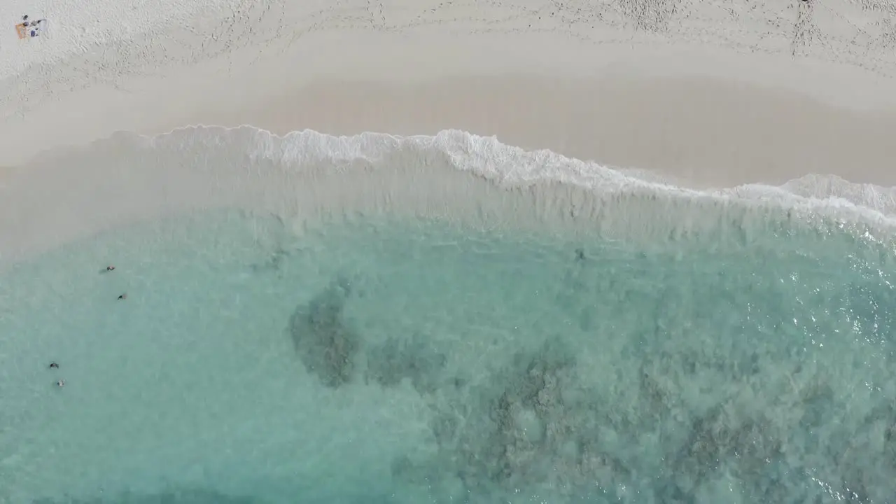 birds eye view of the waves rolling on a beautiful white beach in hawaii