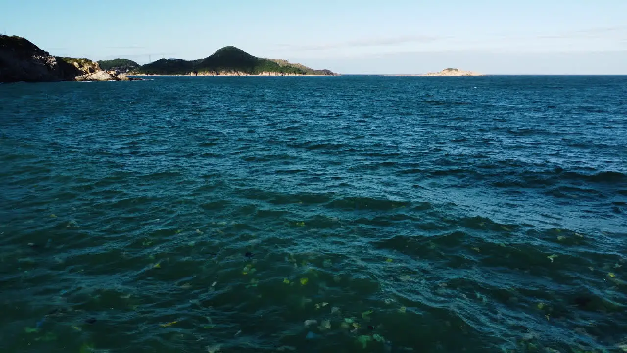 Blue ocean waves filled with single use plastic remains aerial fly backward shot