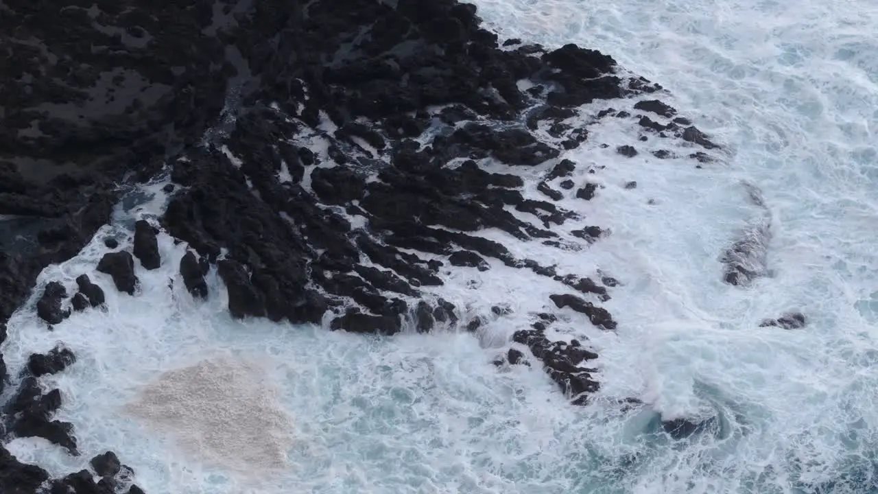 Top down view of rough sea waves hitting rocky coastline aerial