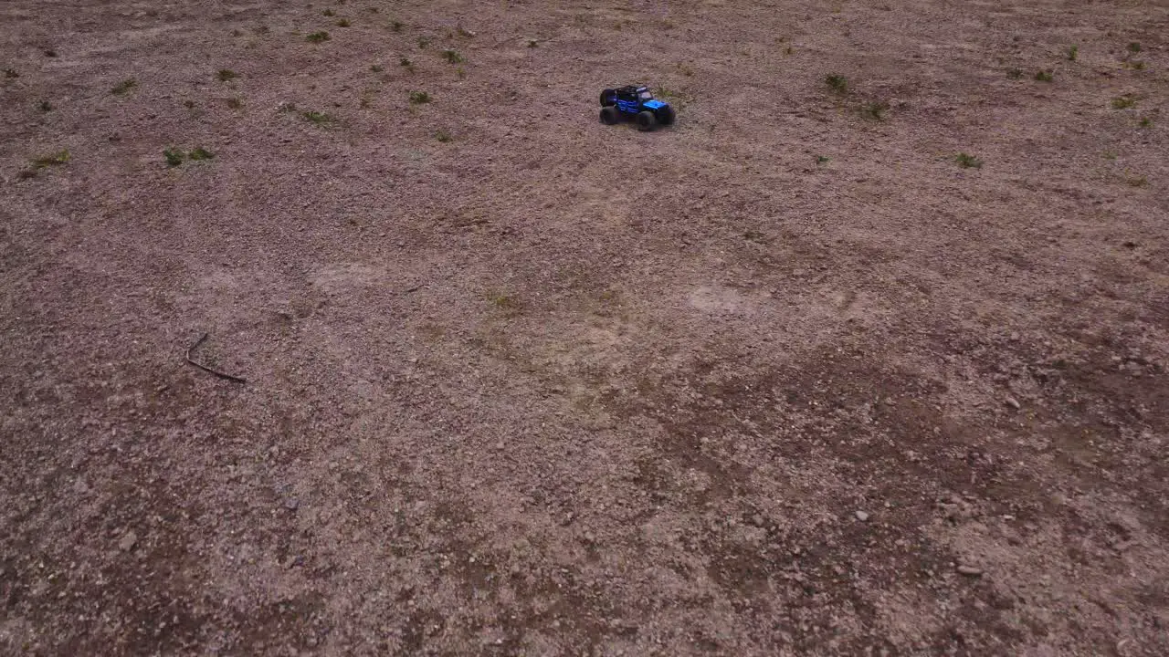 A 4x4 Jeep toy truck drives fast approaching from a leading shot and over rough terrain as seen from high aerial angle