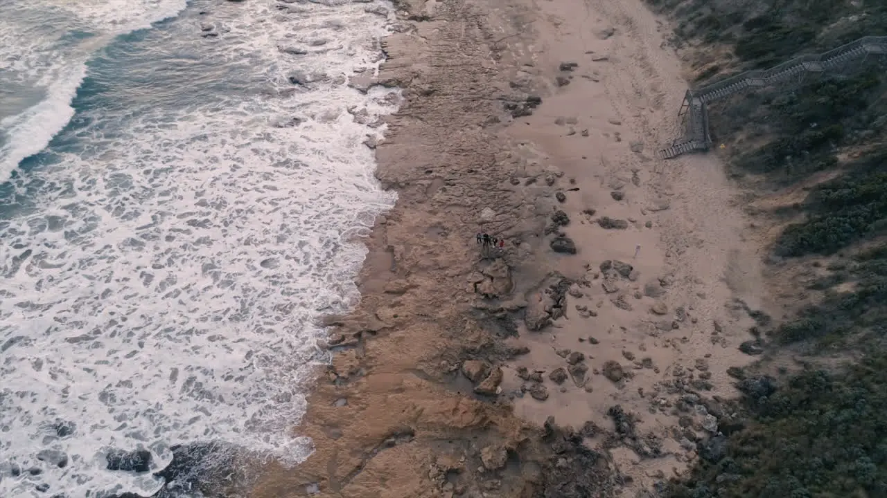 Family on remote beach birds eye view pulling away aerial