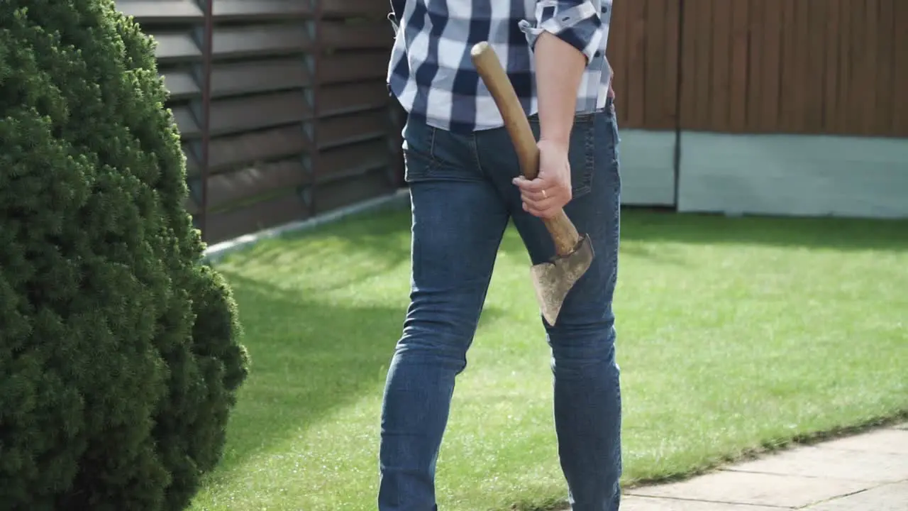 a young man with blue jeans and a blue shirt is walking with the axe in his hand