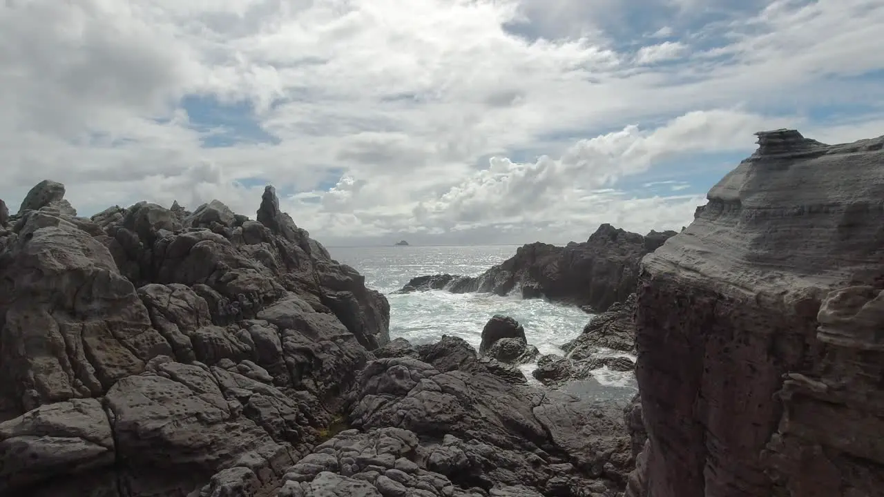 Slow motion waves breaking onto rocks on bright and sunny day