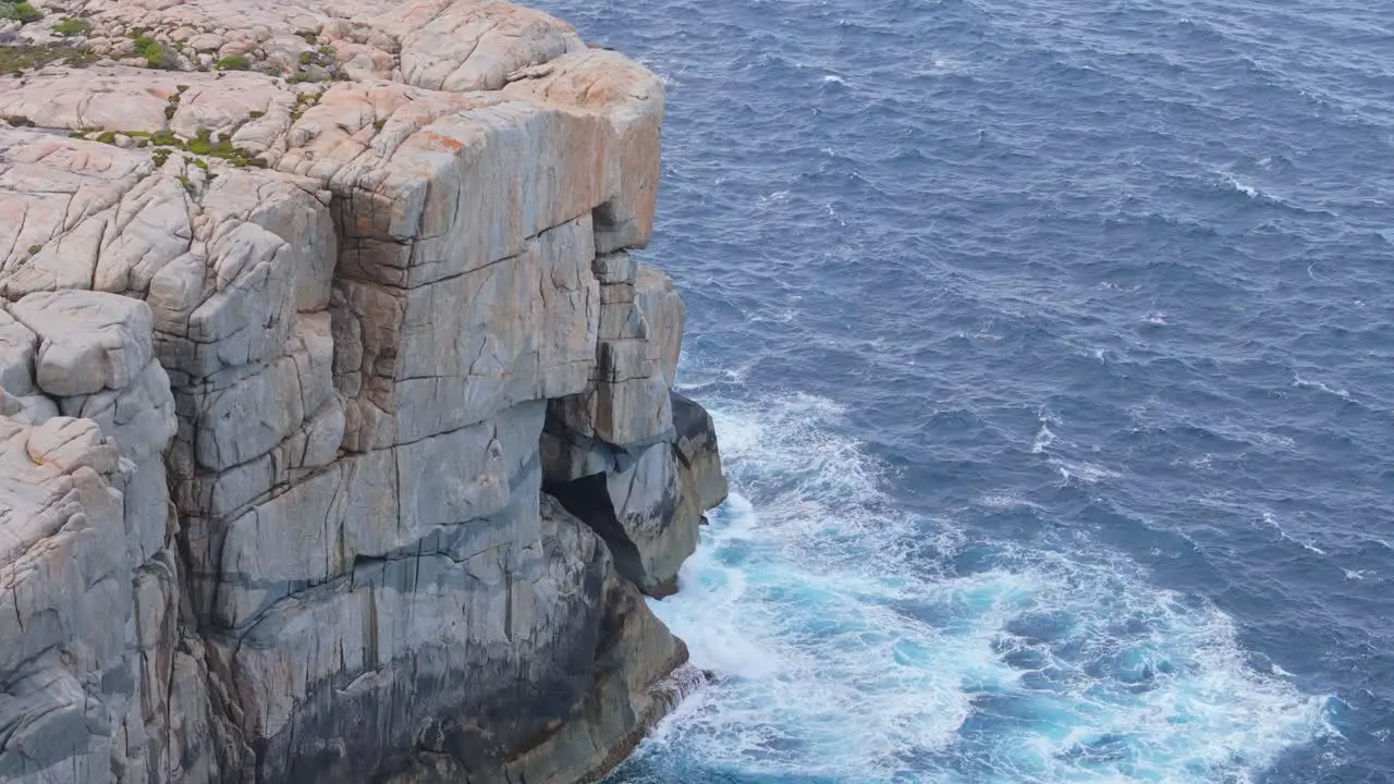 Wild rough waves crash against rocky cliff