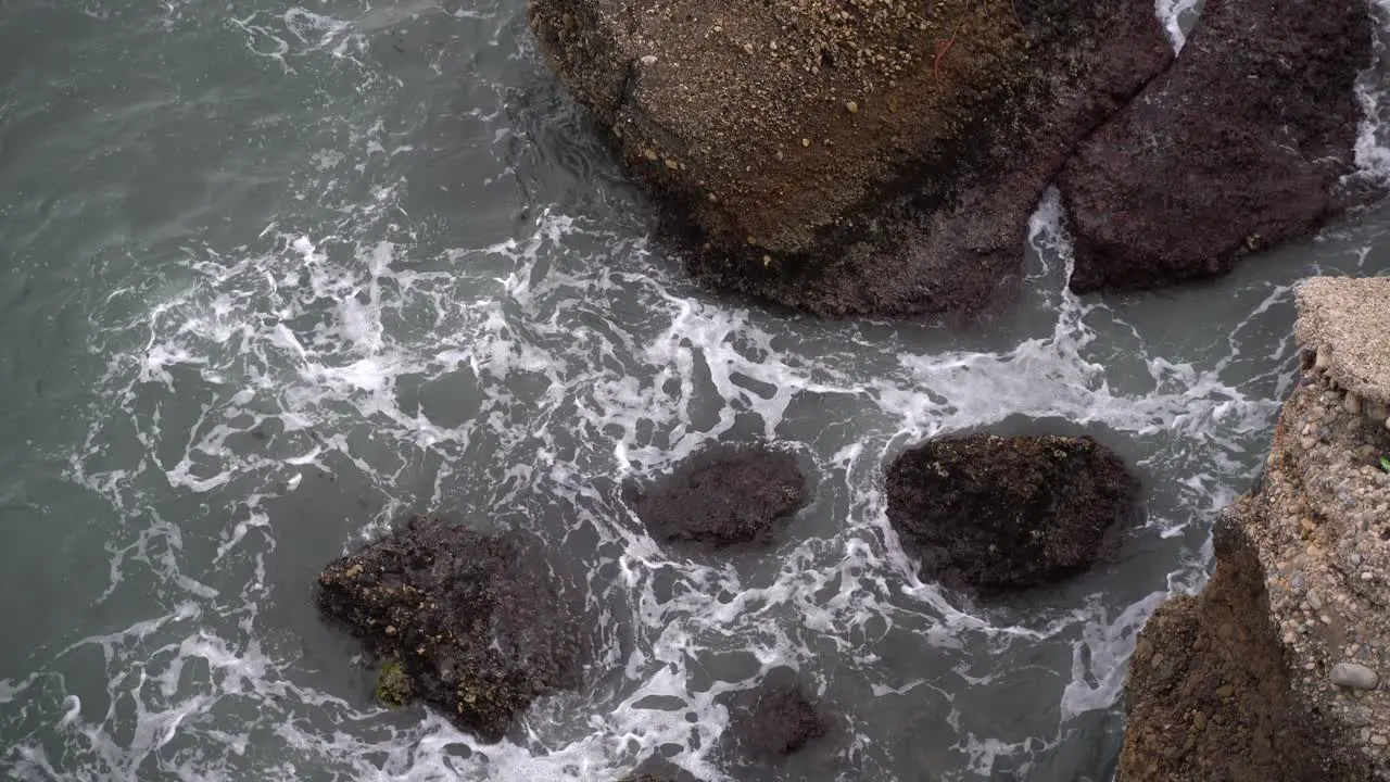 Top down look into ocean with rocks and crashing waves