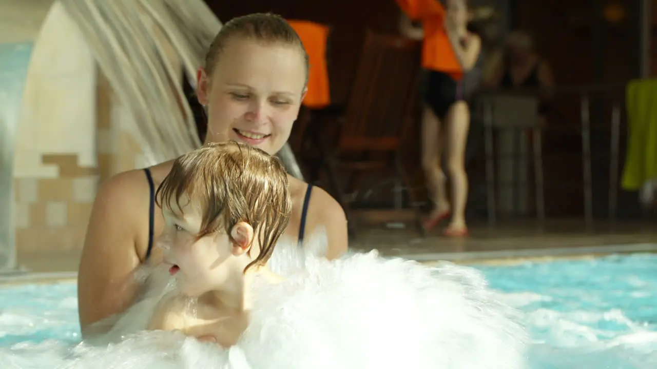 Mother holding son splashing in the rough water of pool