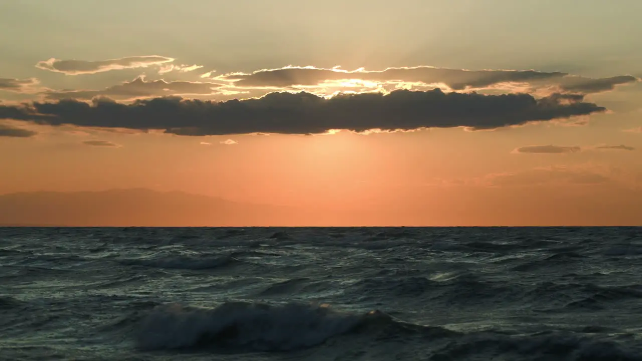 Rough sea and evening sun hidden with cloud